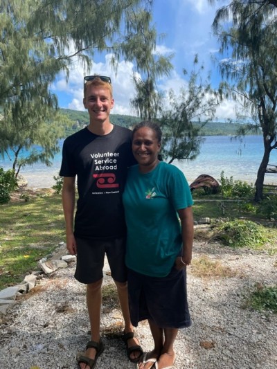A young man and woman smile for the camera on a beach