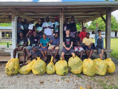 A large group of people smile for the camera with the bags full of rubbish they just collected