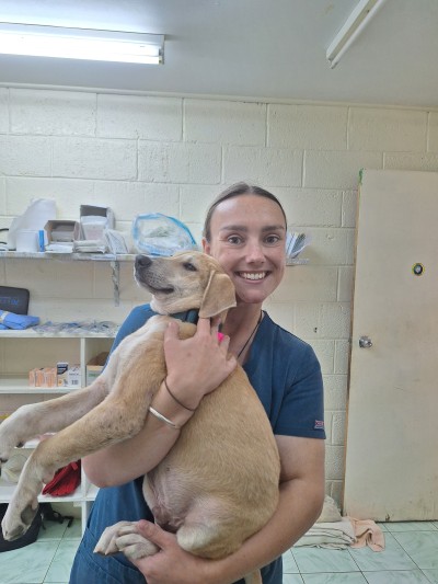 Veterinary nurse smiles for the camera while holding a dog